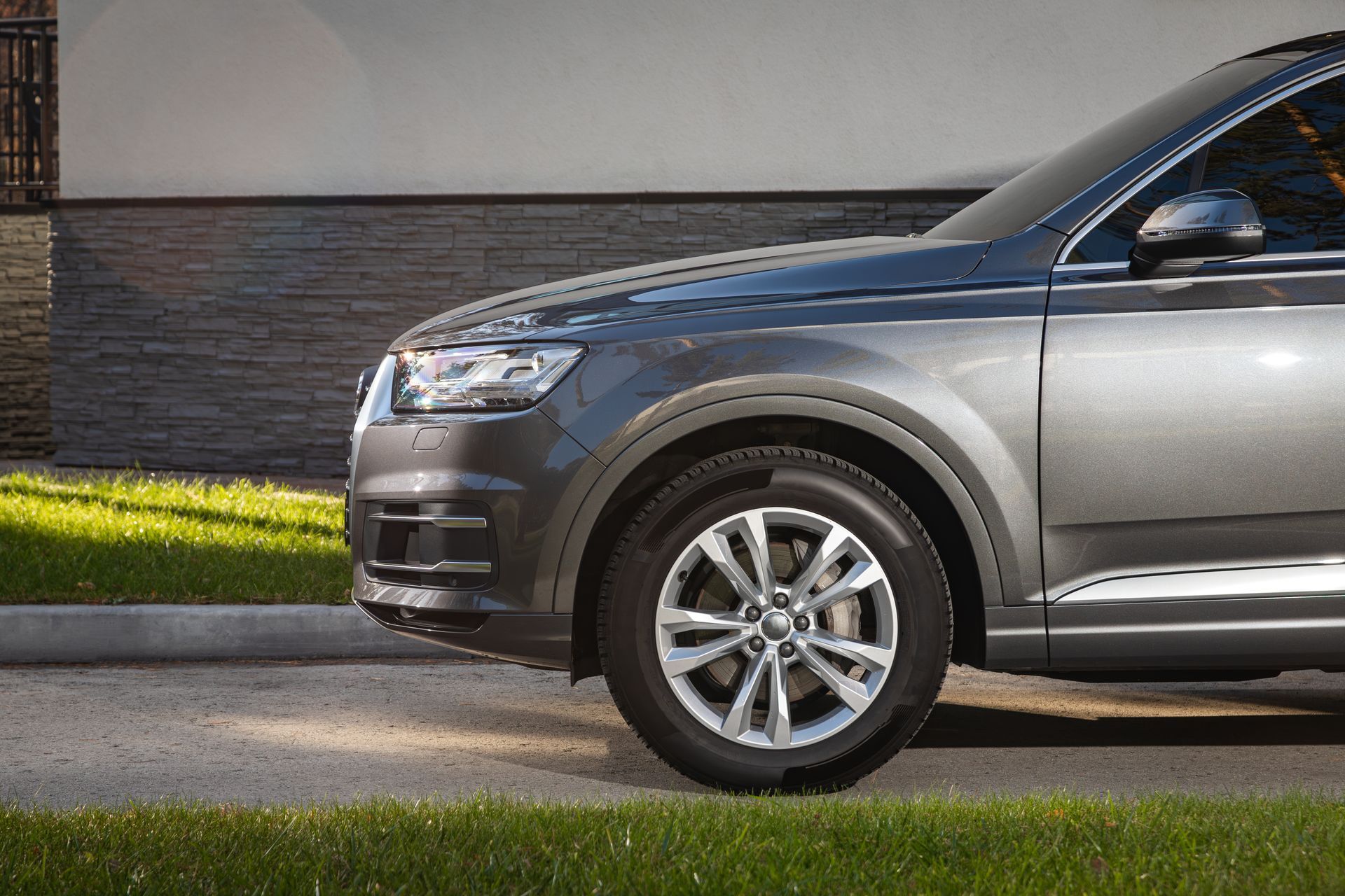 A gray car is parked on the side of the road in front of a building.