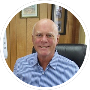 Bald man in a blue striped shirt smiling, seated in an office with wooden paneling. Bald man in a blue striped shirt smiling, seated in an office with wooden paneling.