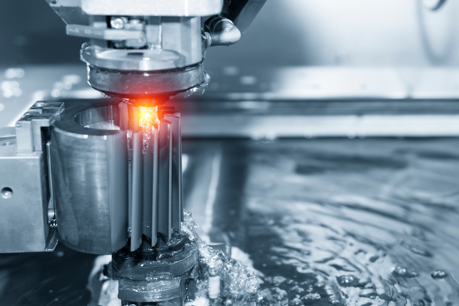 A machine is cutting a piece of metal with a red light coming out of it.