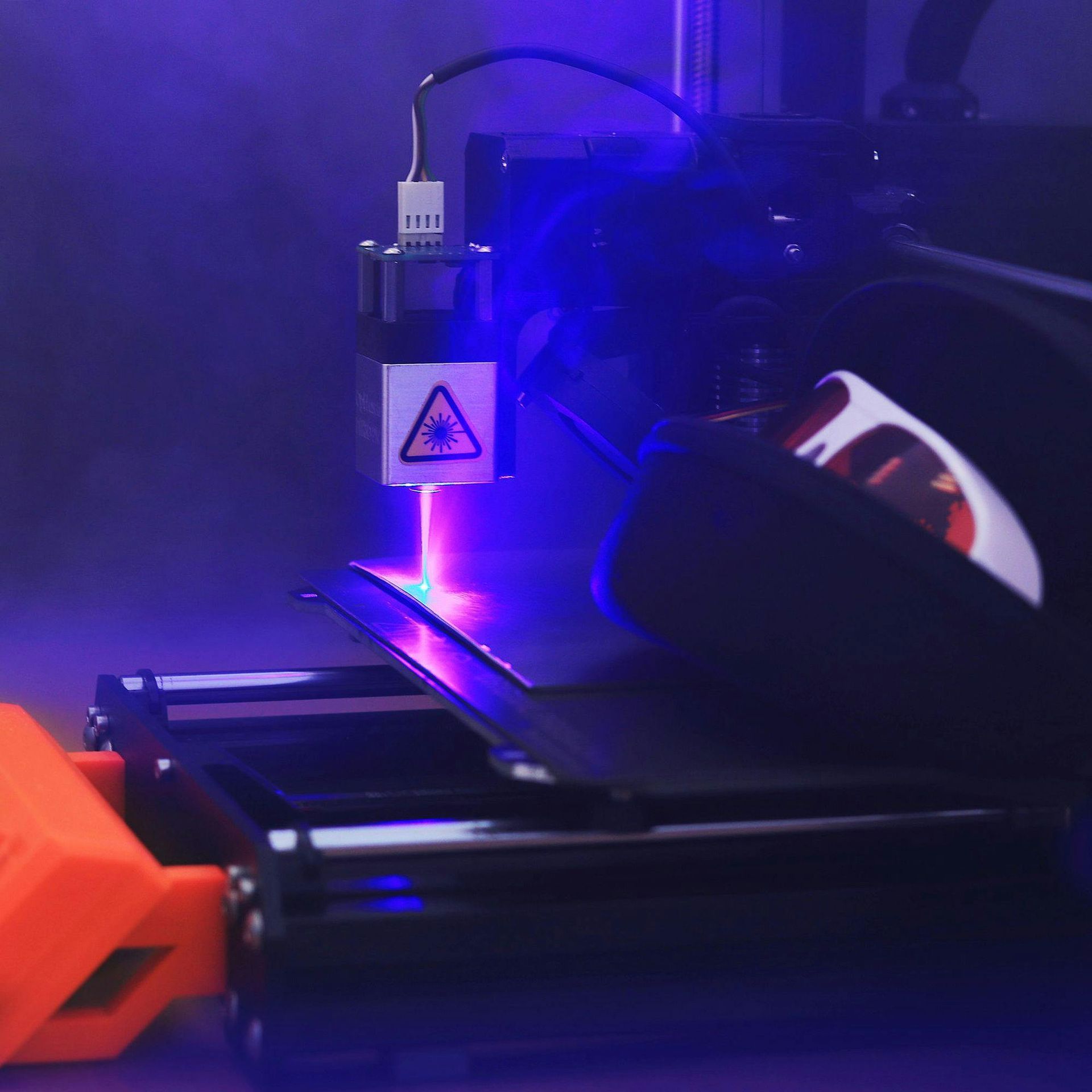 A close up of a laser cutting machine with a purple light coming out of it.