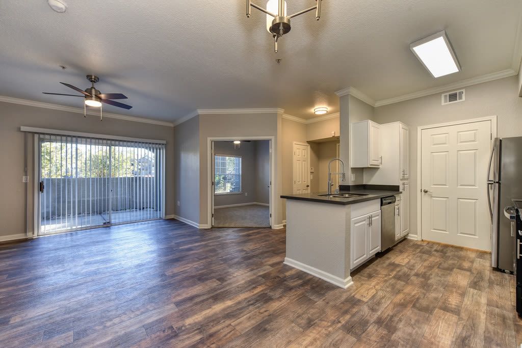 Open-concept apartment with wood floors. Kitchen on the right, living area and balcony on the left.