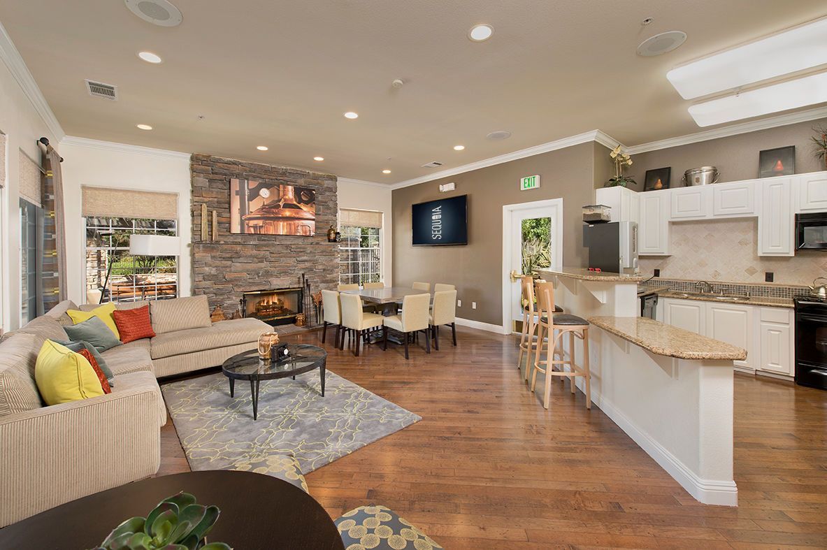 Spacious open-concept living area with a stone fireplace, dining table, kitchen, and seating.