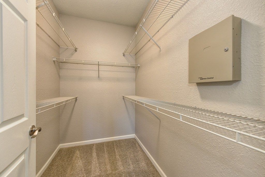 Walk-in closet with white wire shelves and beige walls