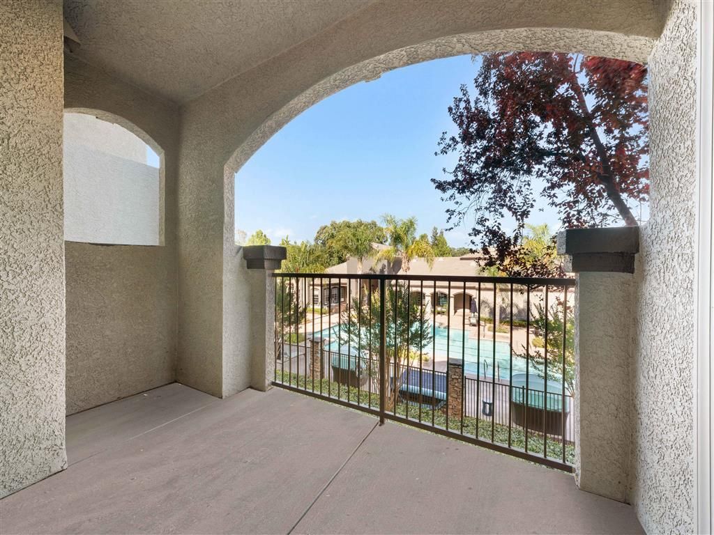 Balcony with railing overlooking a communal pool in an apartment community.