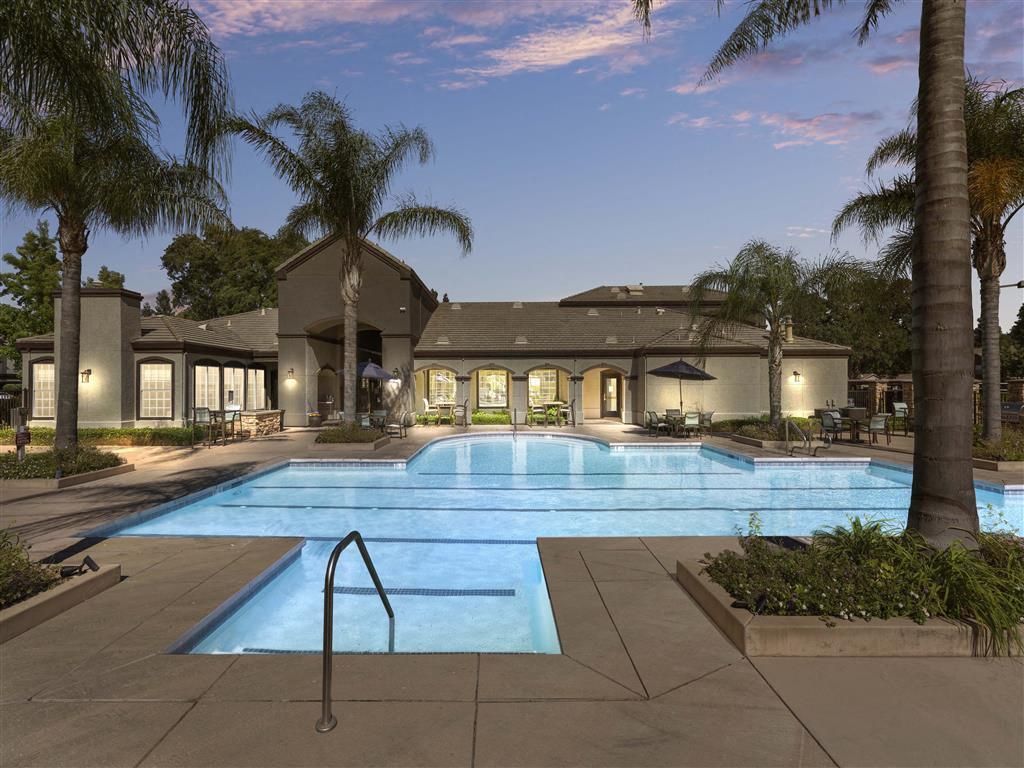 Outdoor pool at a residential community with palm trees and seating areas.
