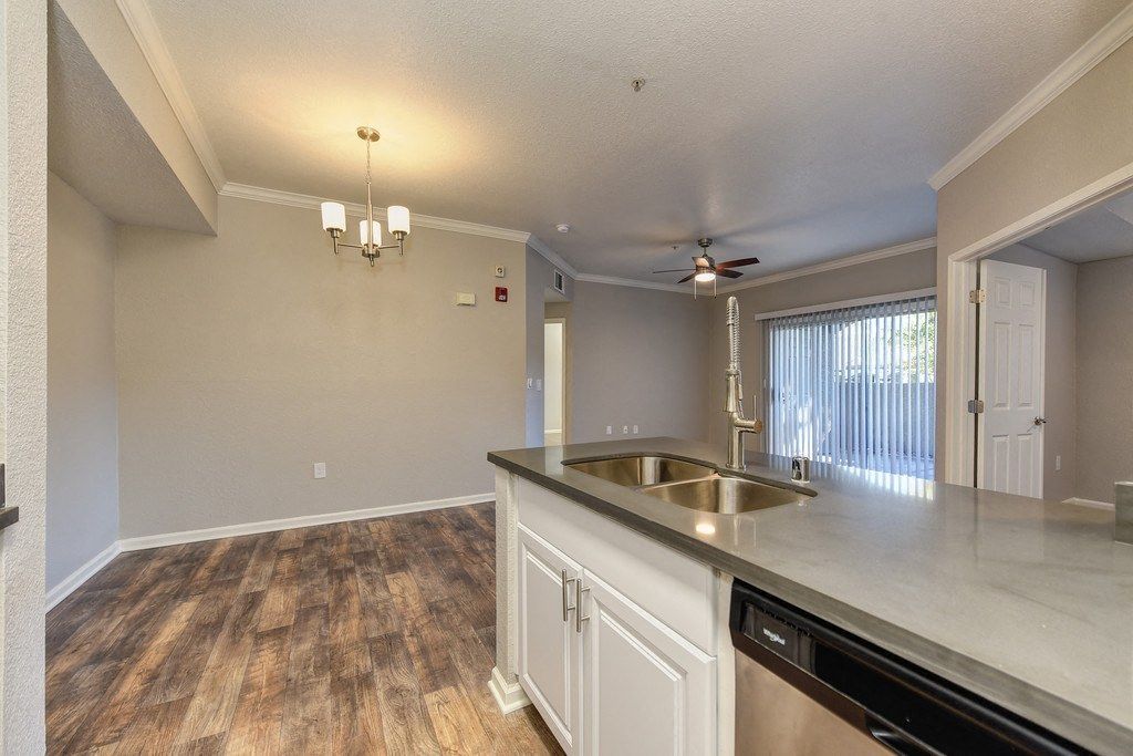 Open-concept apartment kitchen with island, double sink, and laminate flooring.