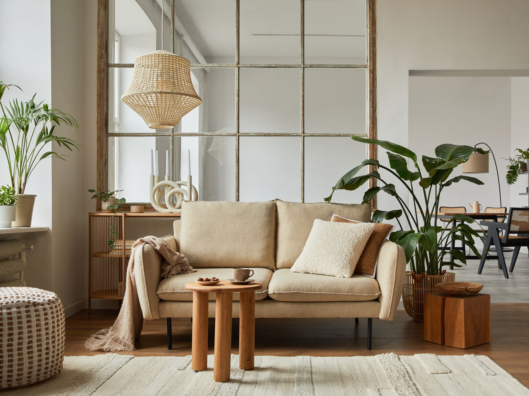A living room with a couch , two tables , and plants.
