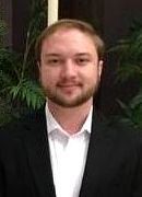 A man with a beard is wearing a suit and white shirt.