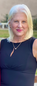 A woman with blonde hair is wearing a black dress and a necklace.