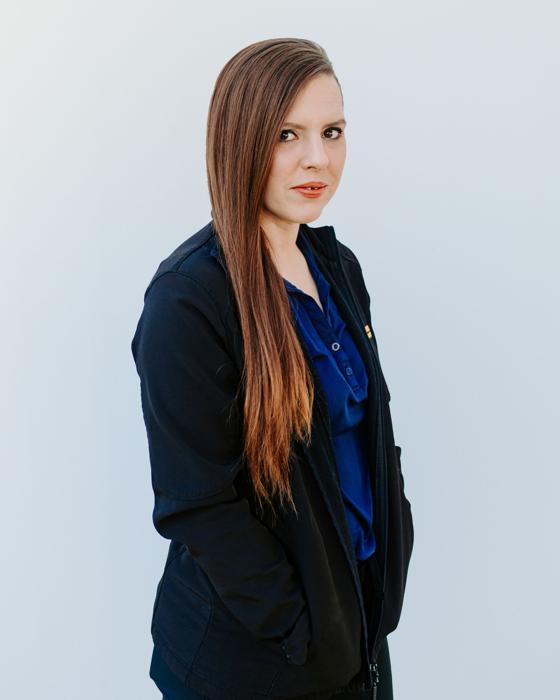 A woman with long hair is wearing a black jacket and a blue shirt.