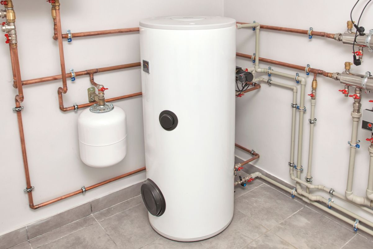 White water heater and associated copper pipes in a utility room, with valves and control panels.