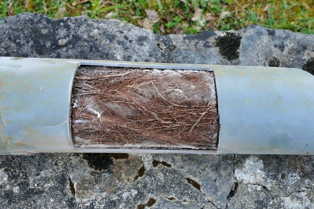 A piece of wood is sitting on top of a metal pipe.