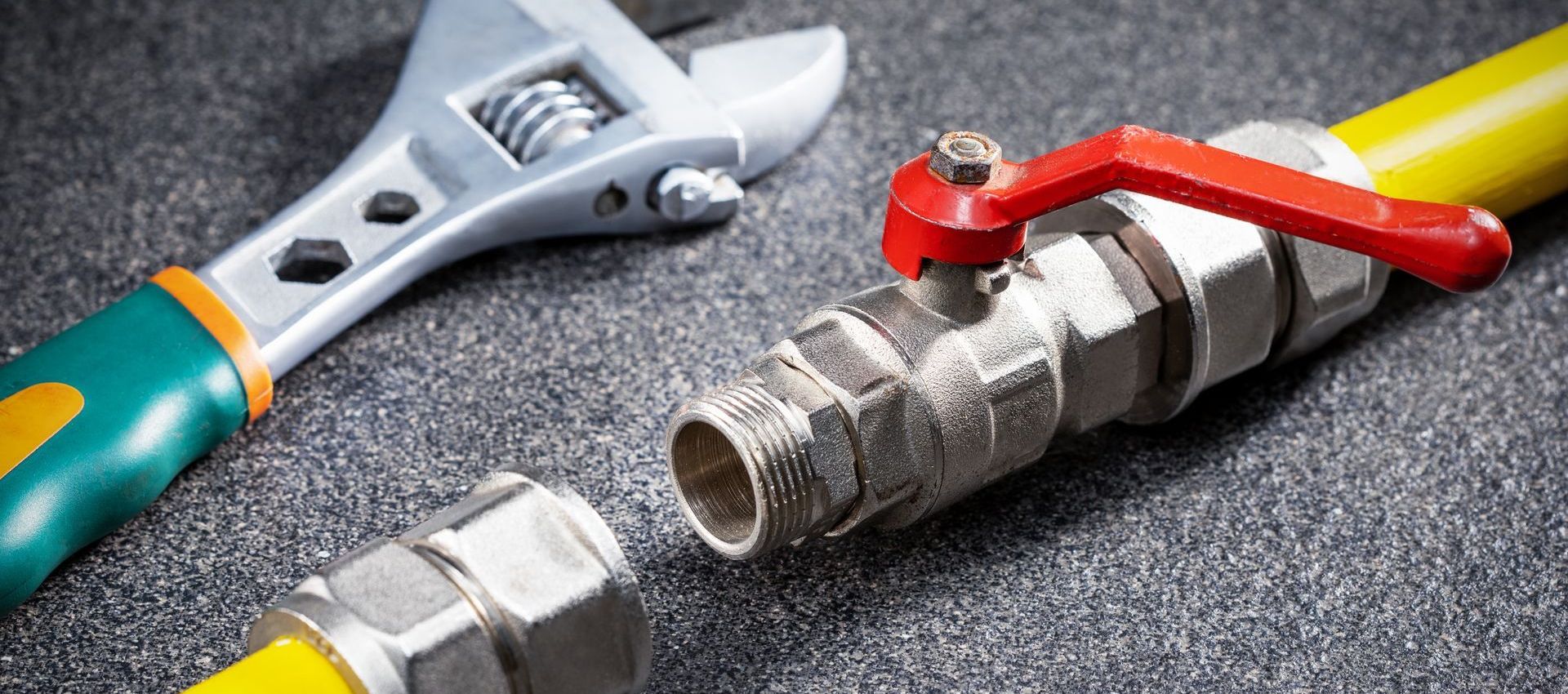 A close up of a gas pipe with a wrench and a valve.