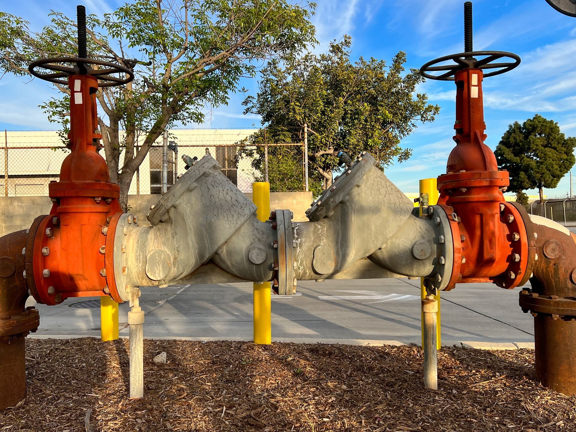 Two red valves are connected to each other on a concrete surface.
