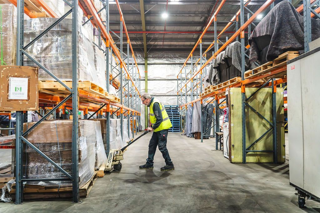 A man is using a tablet in a warehouse.