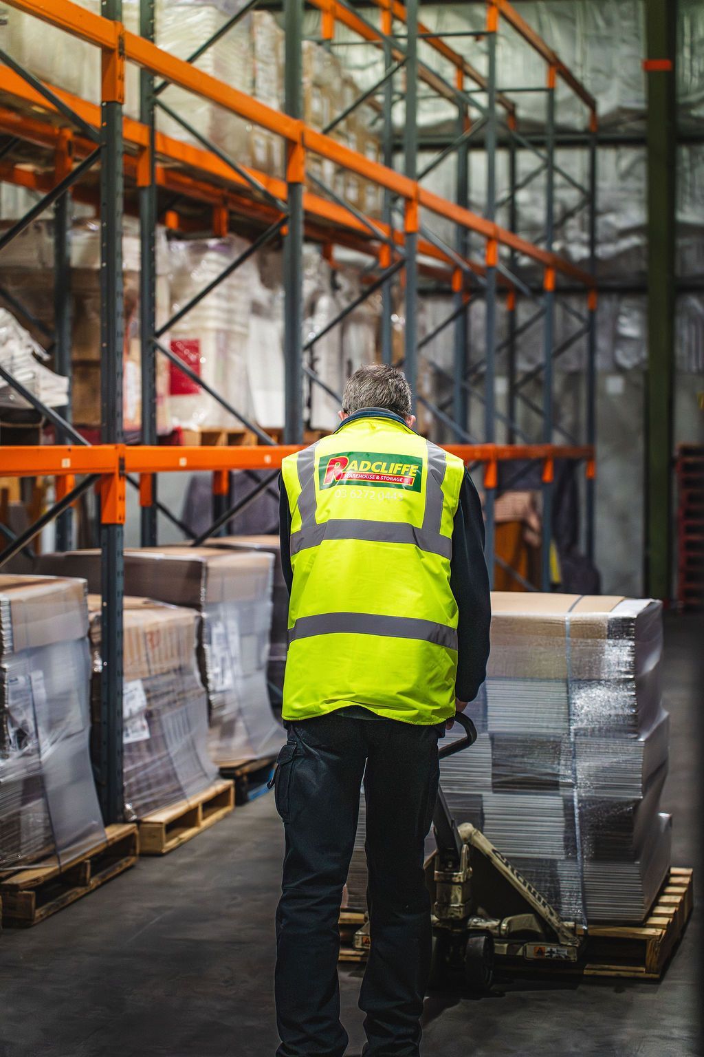 A man is pushing a cart with boxes in a warehouse.