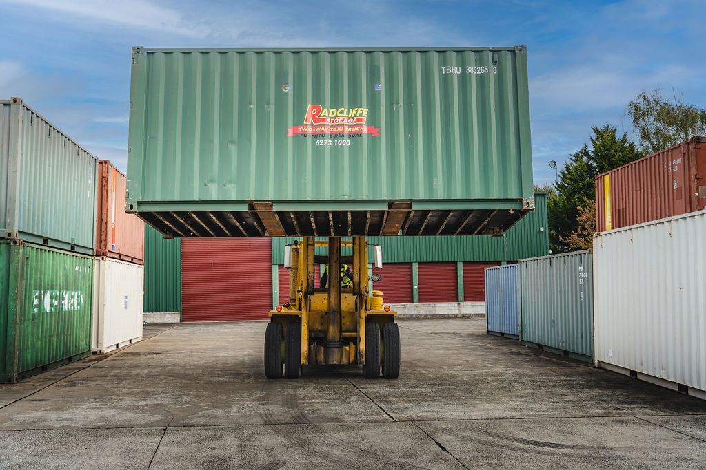 A man is standing in a warehouse holding a hand truck.