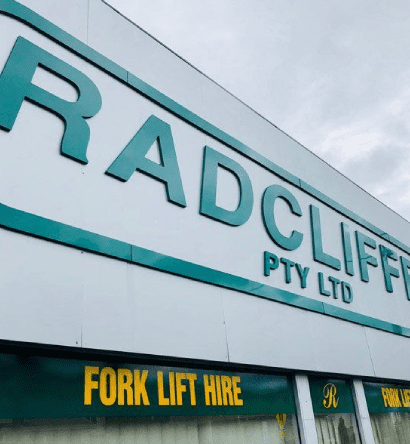 A man is standing in a warehouse holding a hand truck.