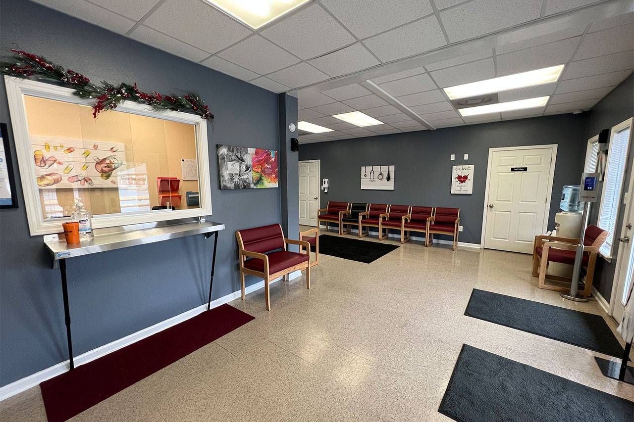 A waiting room with chairs , a counter and a window | Arkansas Spine and Pain