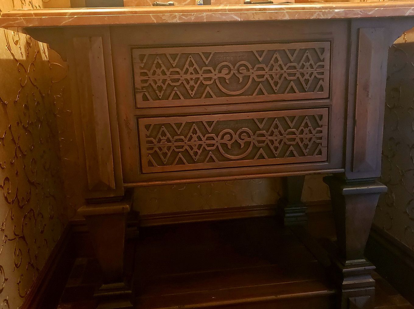 Wooden console table with two drawers, each with ornate carved panels.