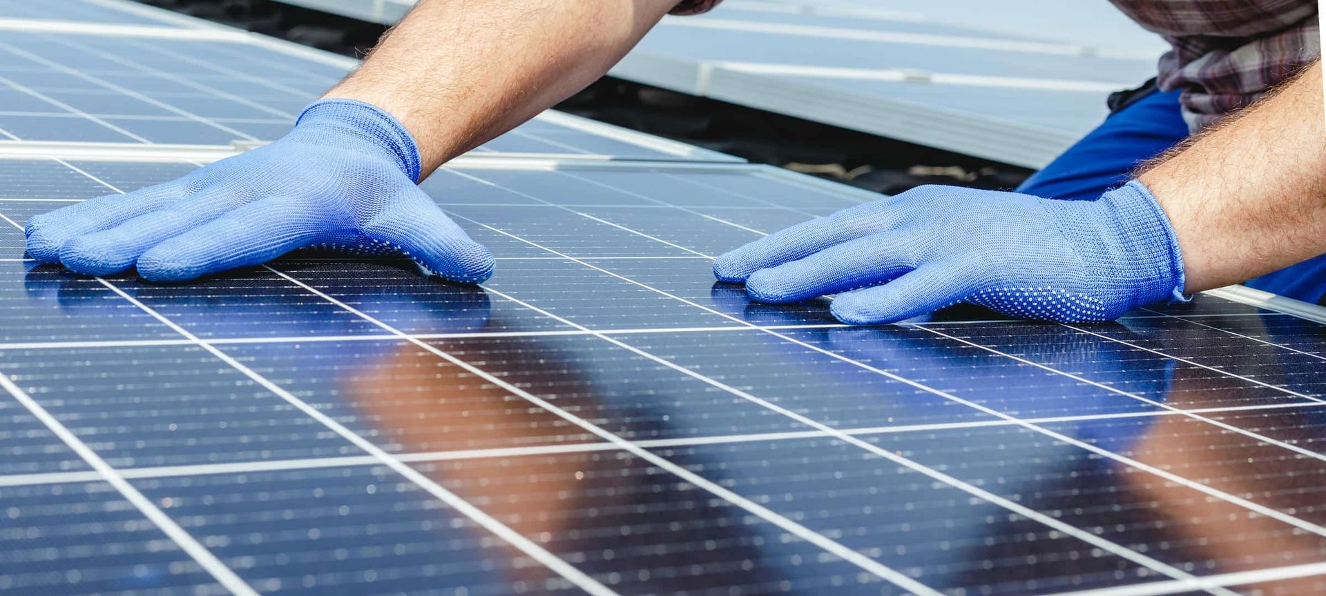 Hands in blue gloves on solar panels.
