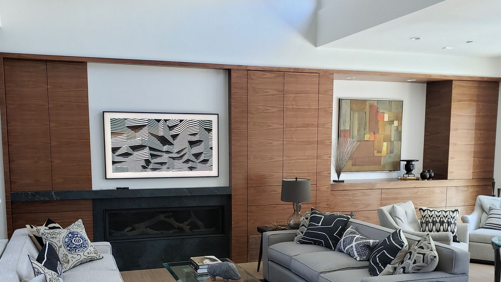 Living room with fireplace, abstract art, and two sofas with throw pillows.