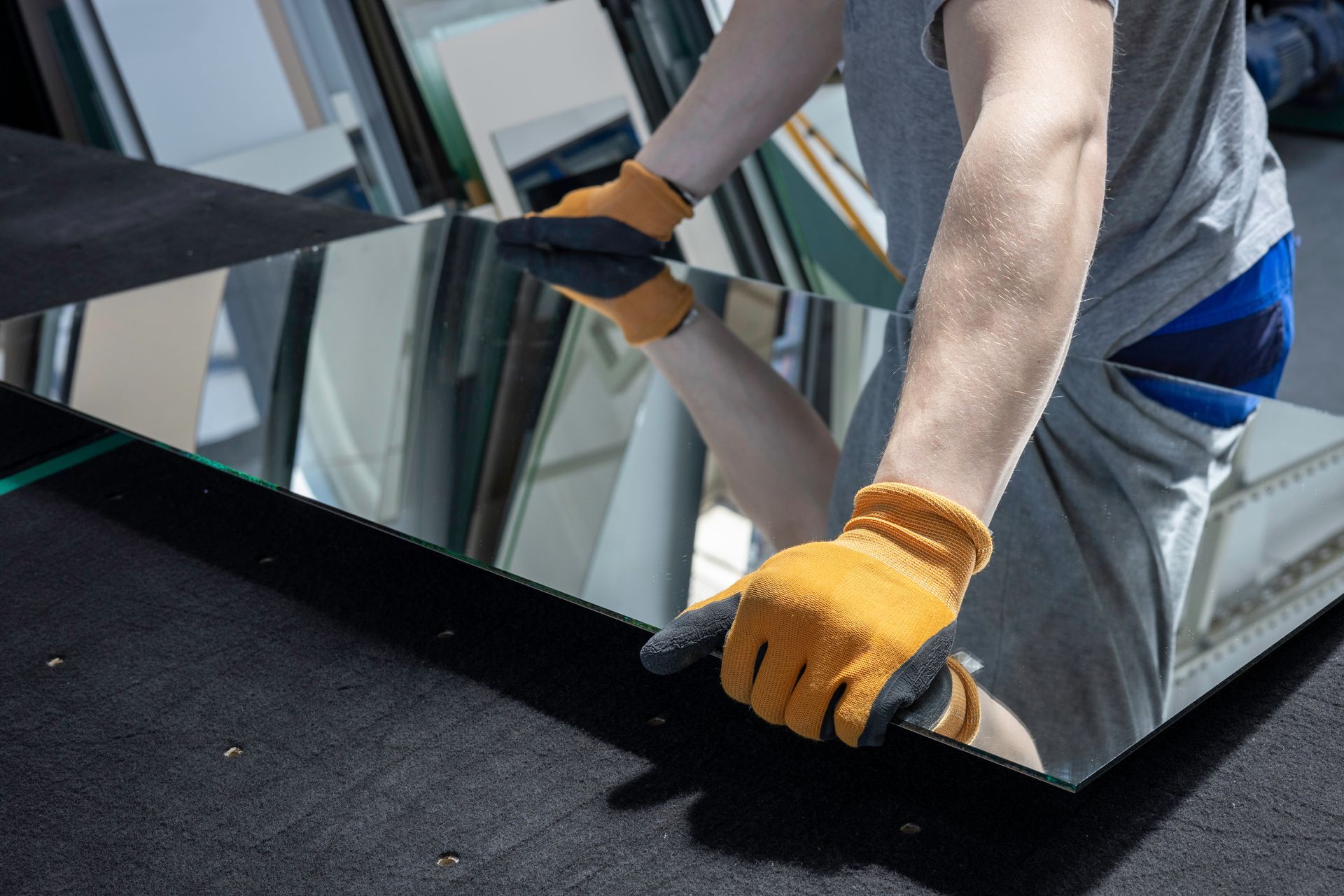 Gloved worker carrying a large glass pane at a construction site