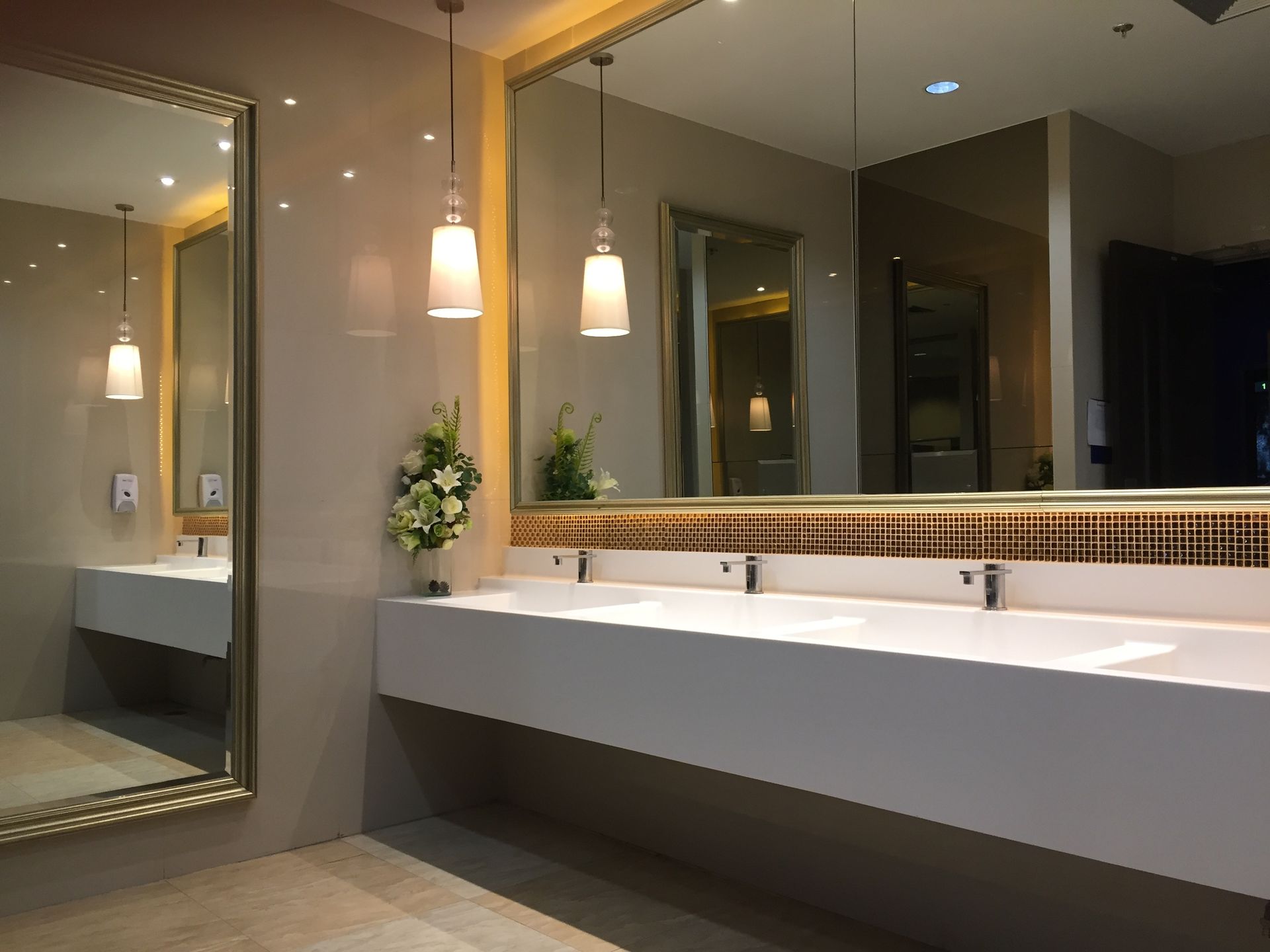 Modern bathroom vanity with double sinks, mirrors, and pendant lights in warm neutral tones