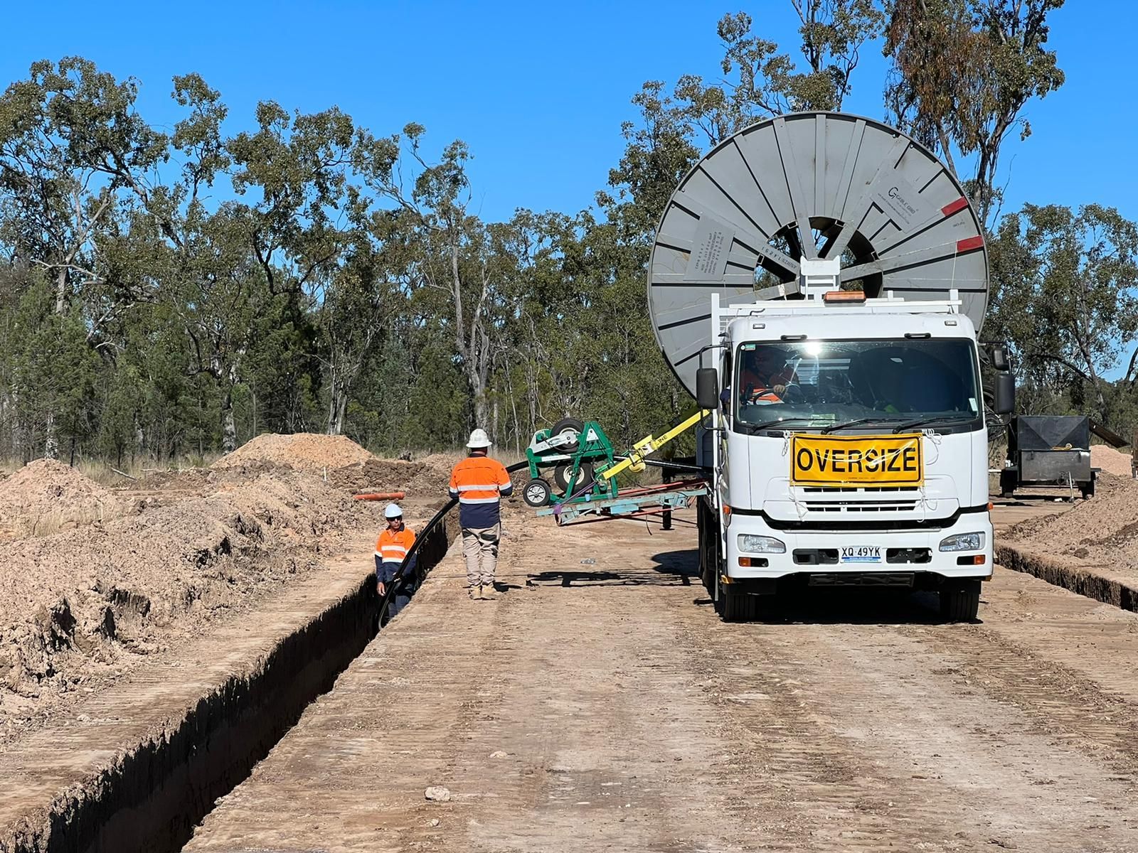 A white truck with a yellow sign on the front that says oversize