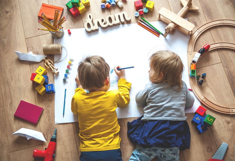 Two Young Children Drawing on Paper Surrounded by Toys — Five Star Family Day Care in Port Stephens, NSW