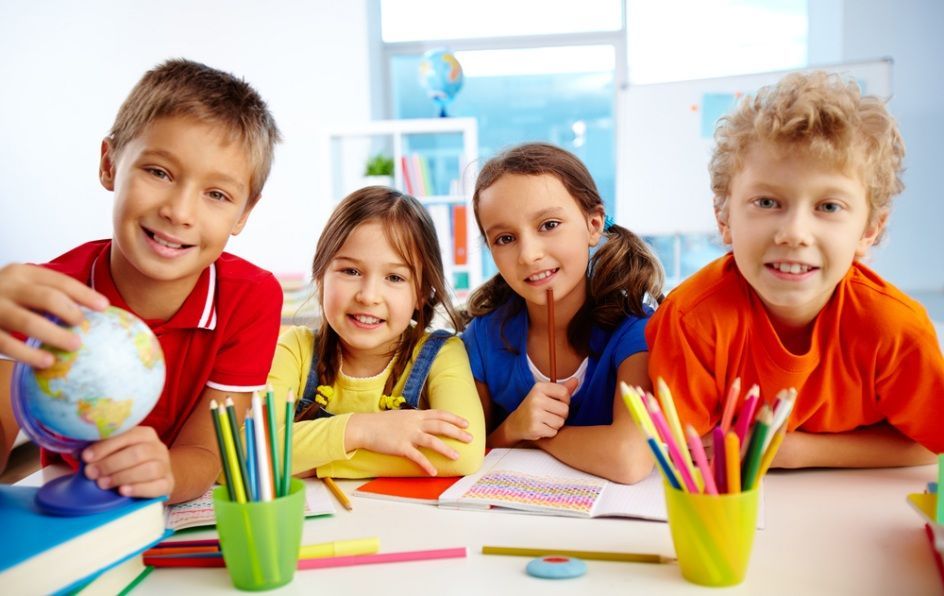 Four Smiling Children at a Desk in a Classroom  — Five Star Family Day Care in Port Stephens, NSW