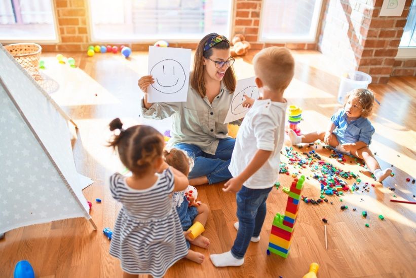 a Teacher Shows Smiley/sad Face Drawings to Four Children — Five Star Family Day Care In Muswellbrook, NSW