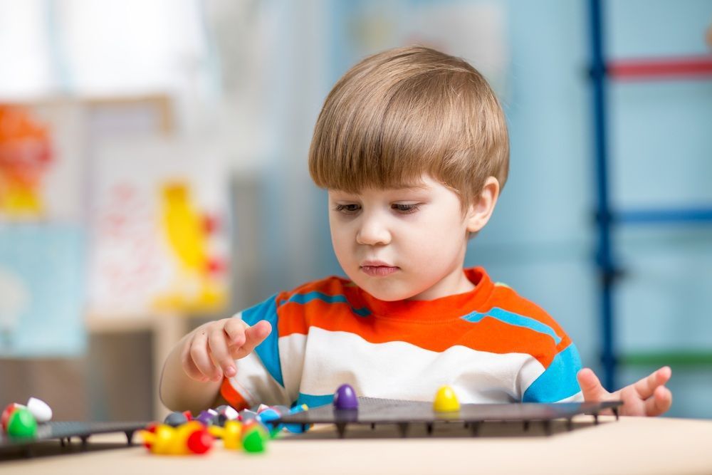 A Young Boy With Light Brown Hair Intently Plays — Five Star Family Day Care in Port Stephens, NSW