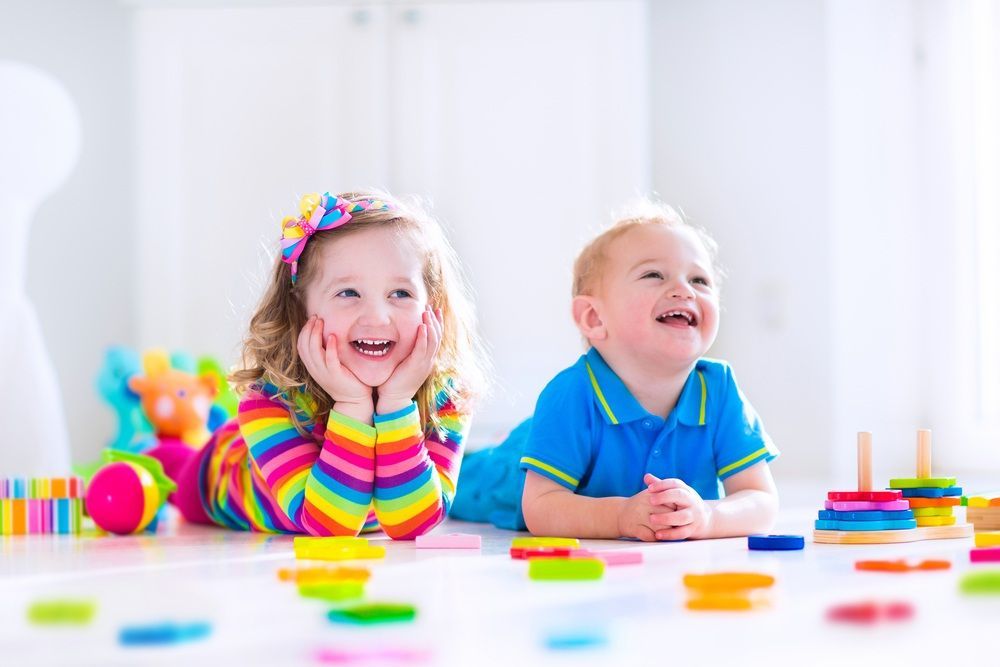 Two Smiling Children Playing With Colorful Toys on a Light-colored Floor — Five Star Family Day Care in Cessnock, NSW