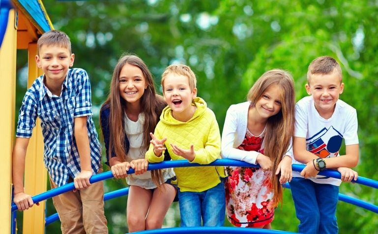Five Smiling Children Pose on a Blue Playground Structure — Five Star Family Day Care In Maitland, NSW