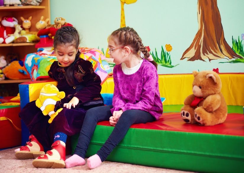 Two Girls Sitting on a Colorful Bench in a Playroom — Five Star Family Day Care In Maitland, NSW