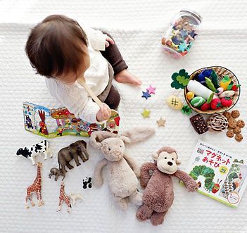 A Baby is Sitting on a Blanket Surrounded by Stuffed Animals — Five Star Family Day Care in Maitland, NSW