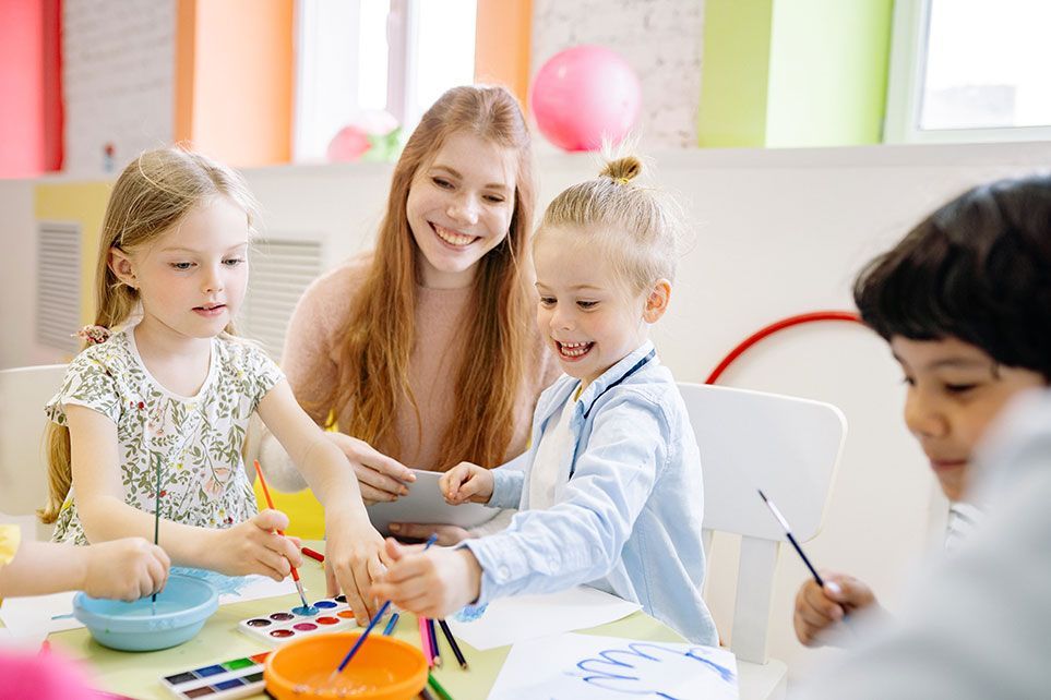 A Group of Children Are Sitting at a Table Painting — Five Star Family Day Care in Maitland, NSW