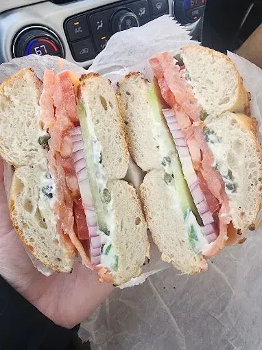 Bagel sandwich cut in half, with smoked salmon, cucumber, red onion, and cream cheese.