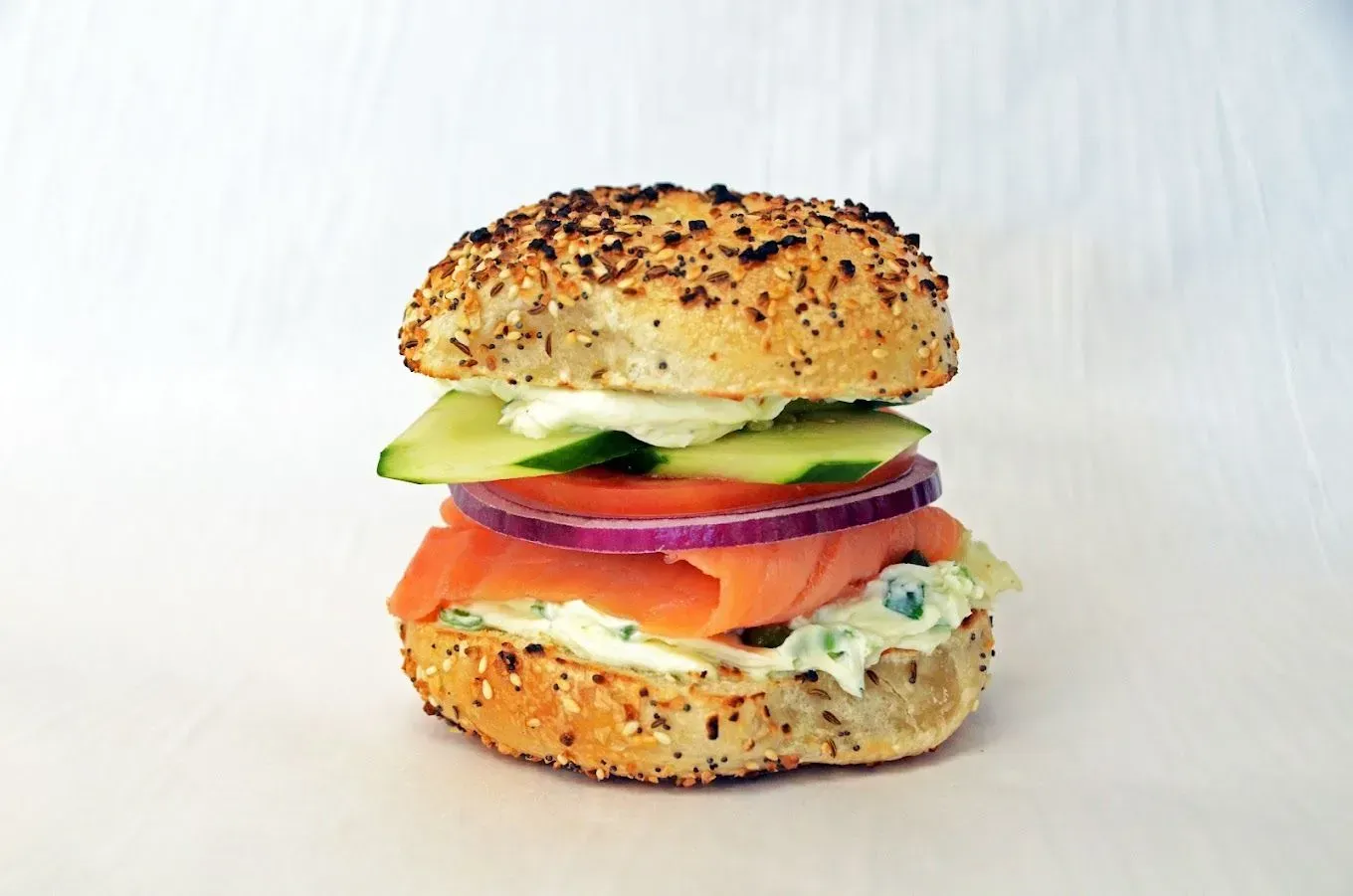Bagel sandwich with salmon, cucumber, red onion, and creamy spread.