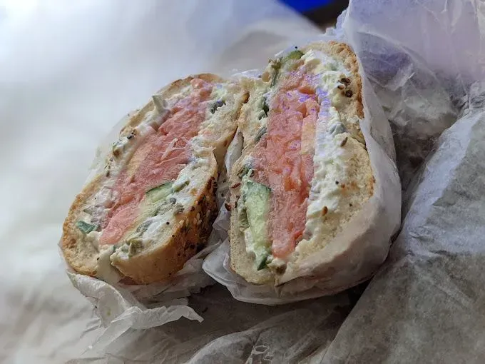 A bagel with cream cheese, smoked salmon, and cucumber, cut in half.