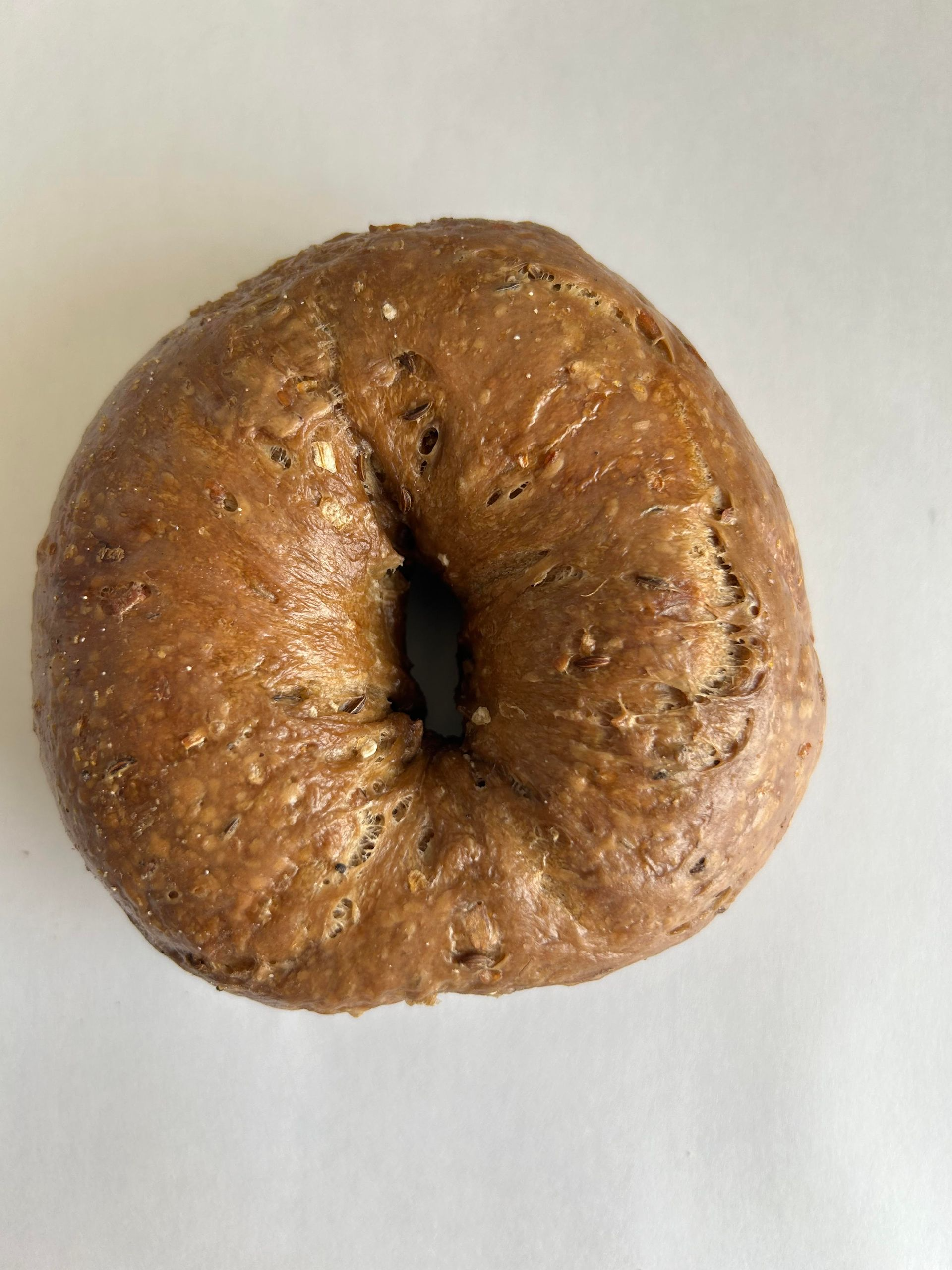 Whole wheat bagel on a white surface.