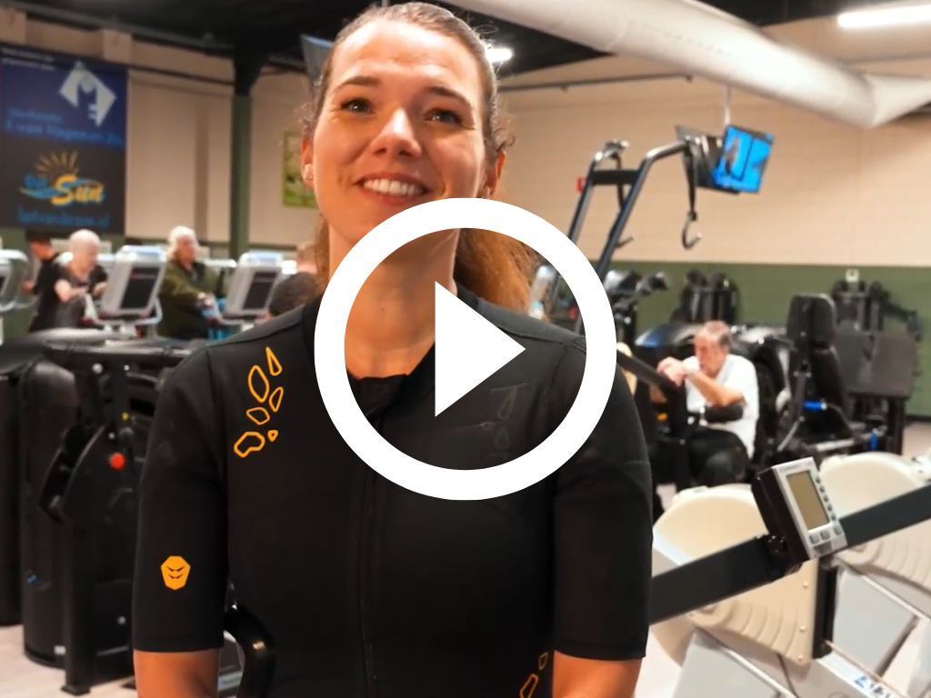 Een vrouw staat voor een afspeelknop in een sportschool.