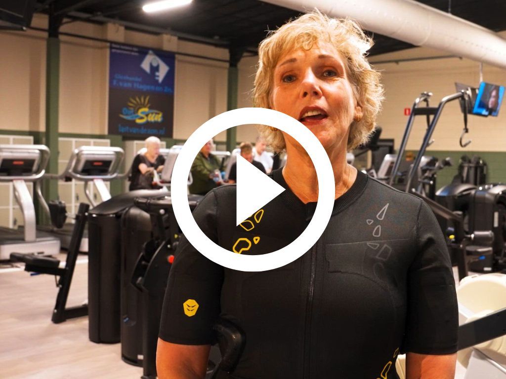 Een vrouw staat in een gymzaal met een afspeelknop in het midden.