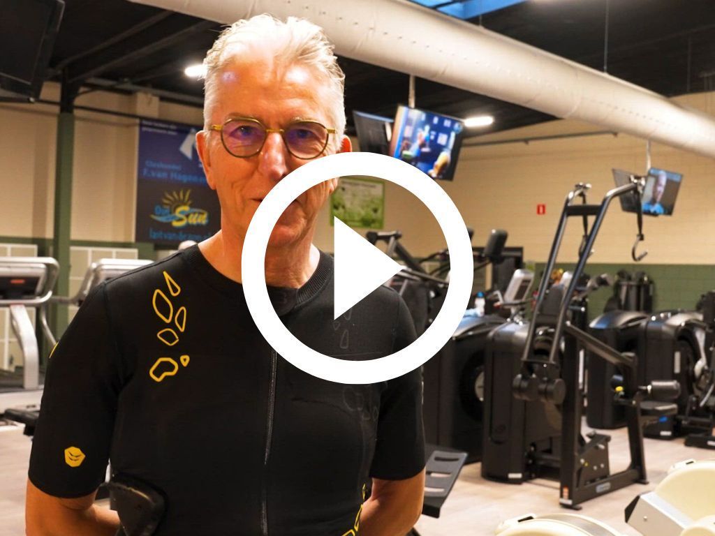 Een man staat in een gymzaal met een afspeelknop in het midden.