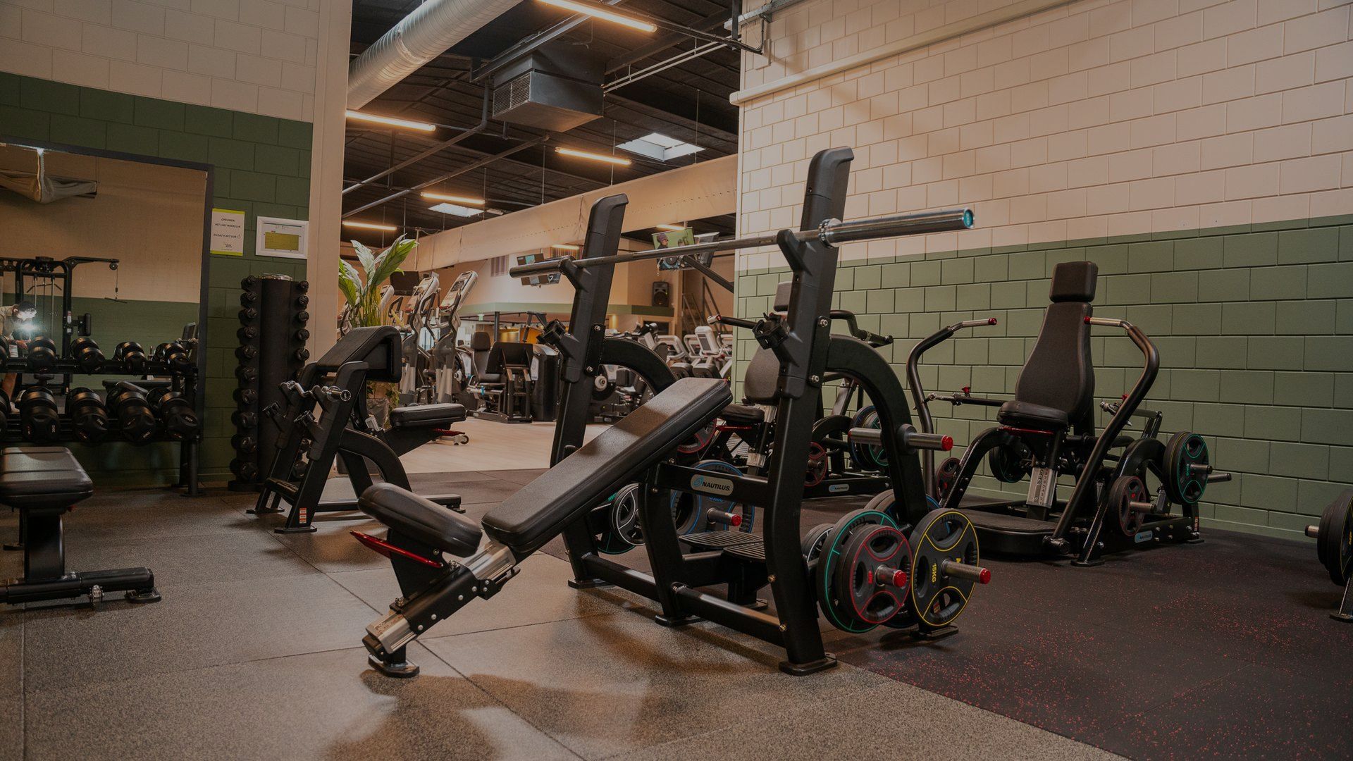 Een sportschool vol met fitnessapparatuur en een bank.