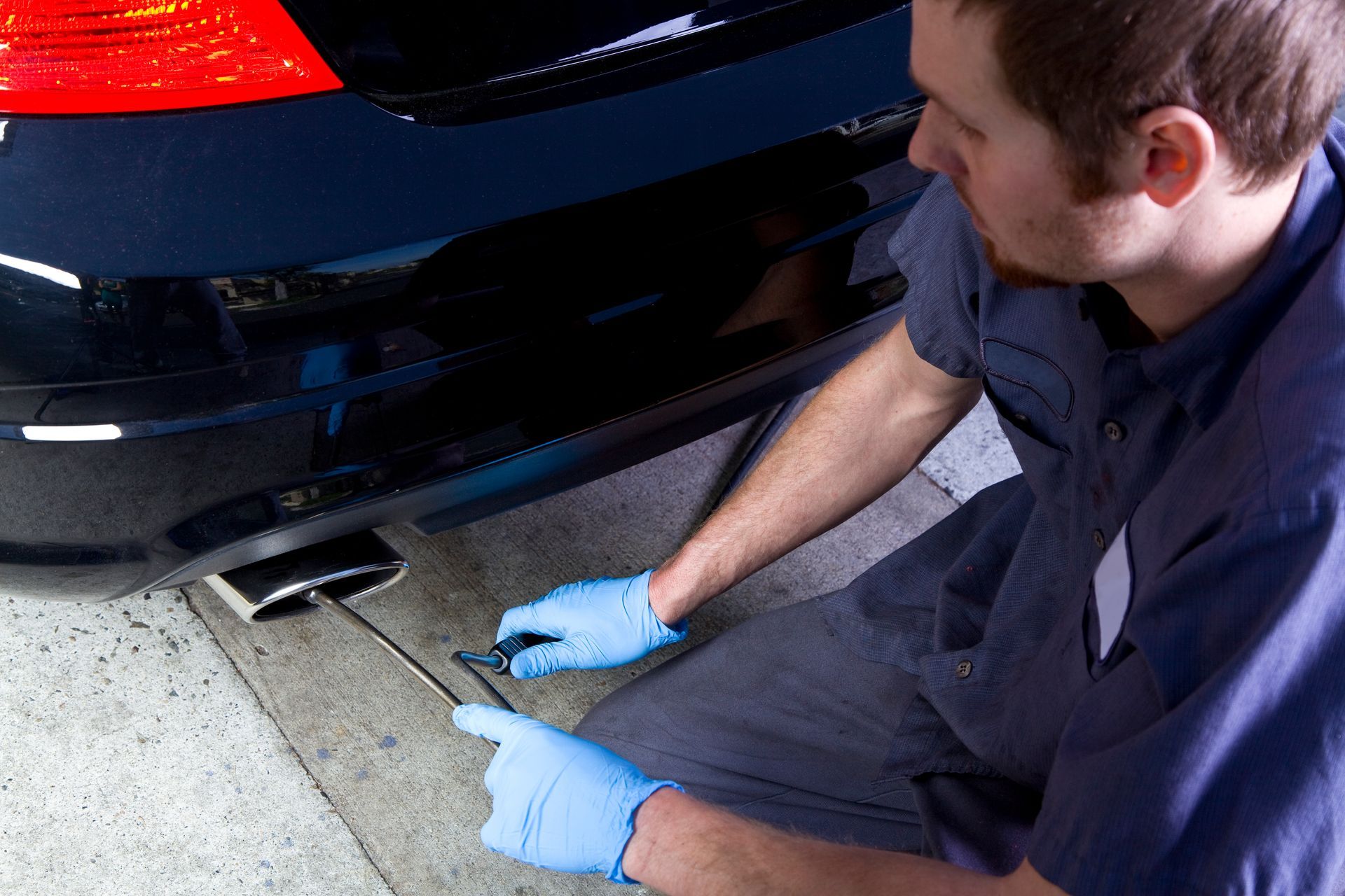 A man wearing blue gloves is working on a car| Ruckersville, VA | KEL-CAM Tire & Auto
