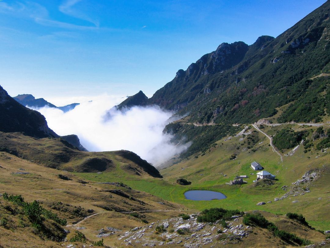 Le montagne sono coperte di nuvole e c'è un piccolo stagno in mezzo alla valle.