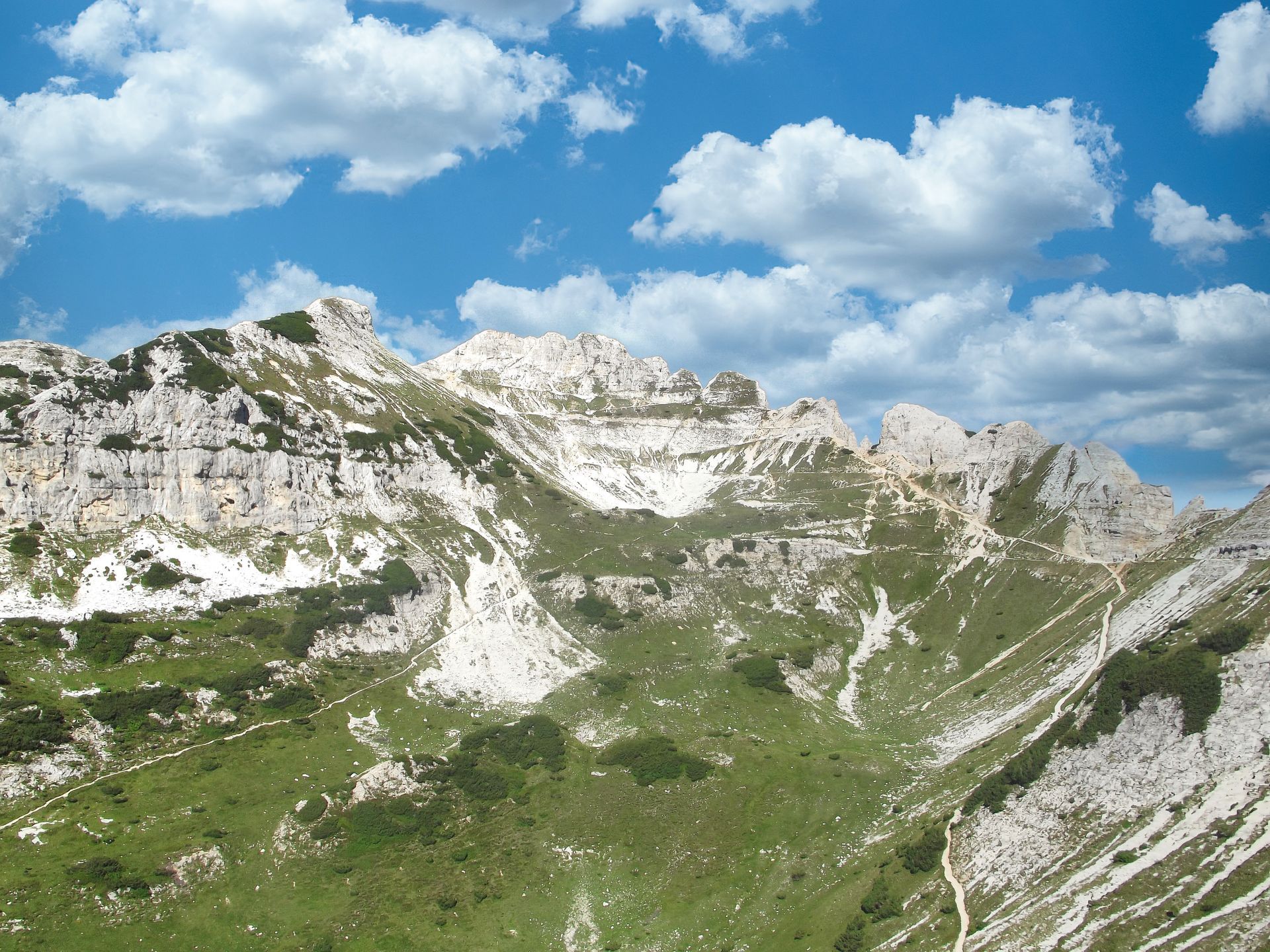 Una montagna ricoperta di erba e rocce con un cielo azzurro sullo sfondo