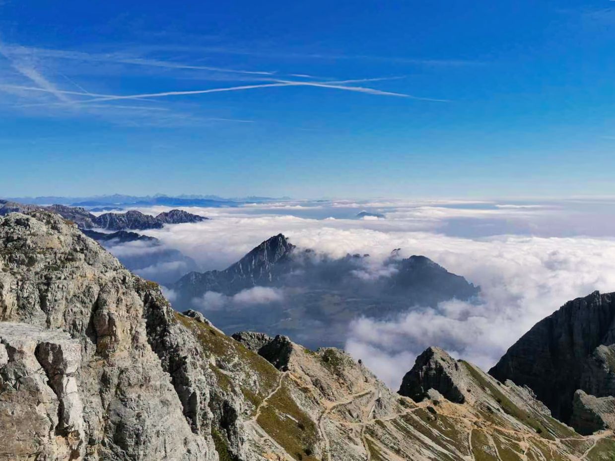Una vista di una montagna coperta di nuvole dalla cima di una montagna.